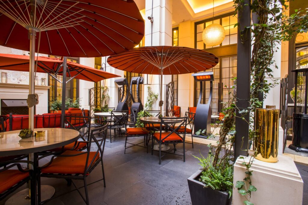 Tabels and chairs with elaborate orange umbrellas covering them and portable heaters